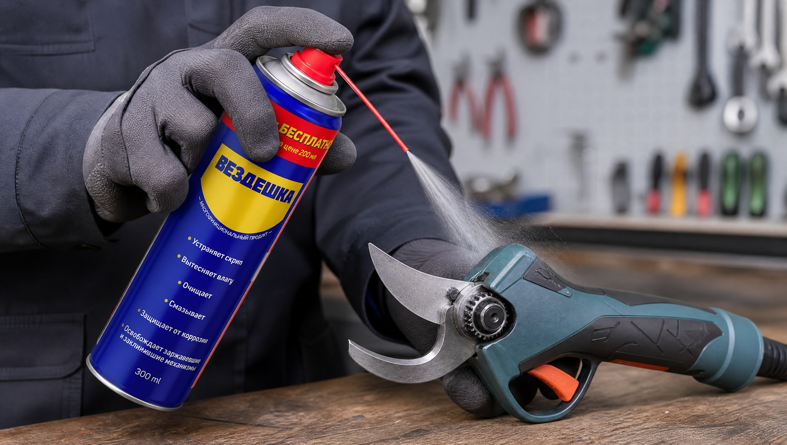 Рука в перчатке наносит универсальную смазку wd-40 на садовый инструмент.
