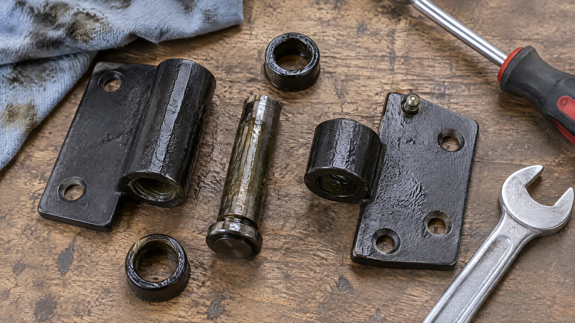 На верстаке лежат разобранные части уличной петли, покрытые тонким слоем WD40.
